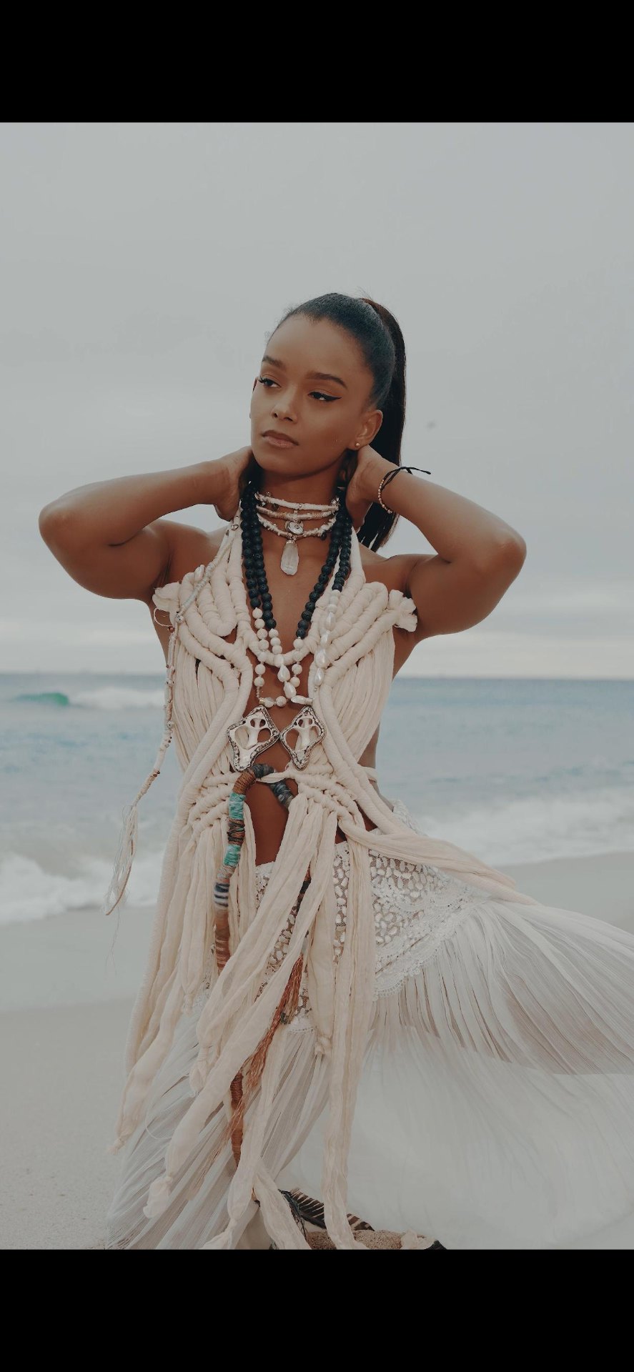 Model in a cream macramé and shell wearable-art gown on the beach